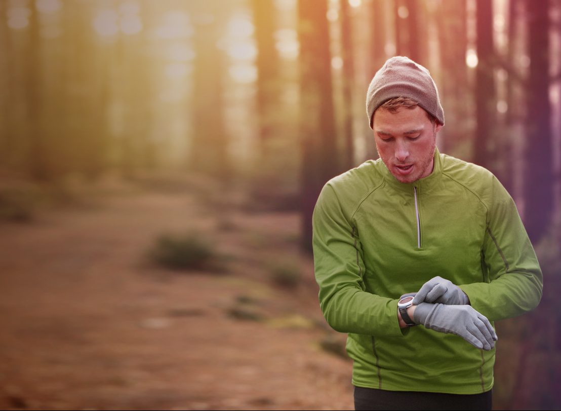 man looking at smartwatching running