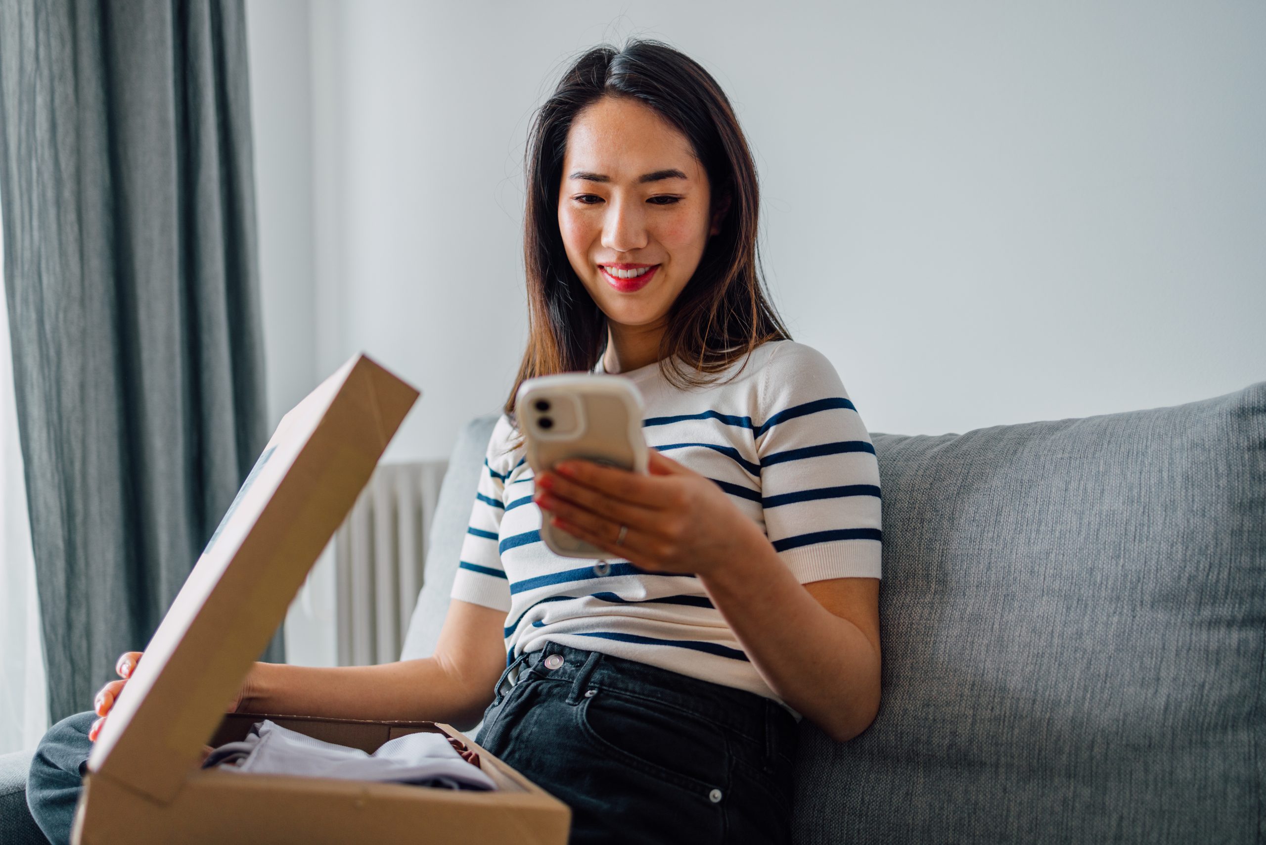 A smiling Japanese woman reviewing the product she bought online.