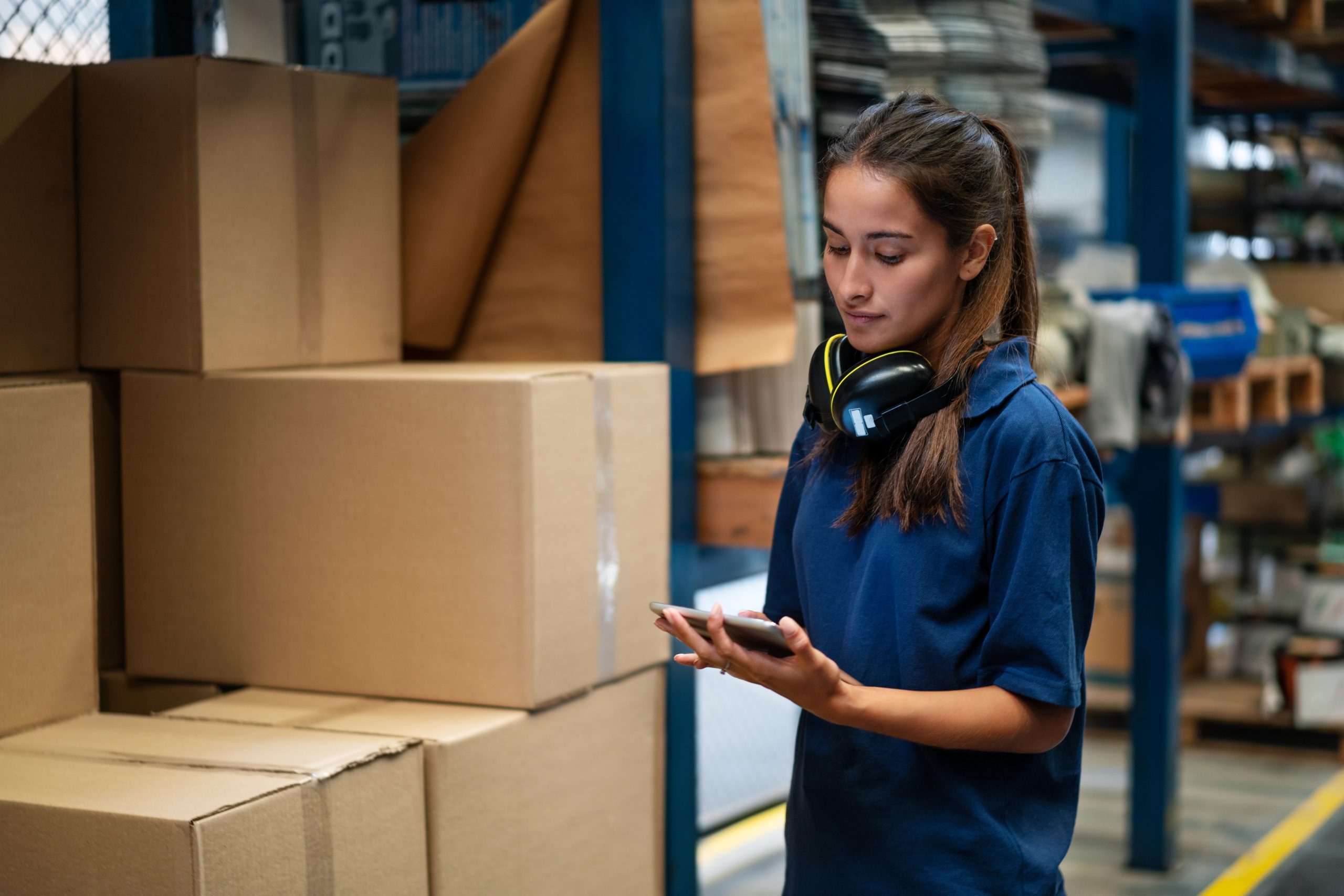Female warehouse worker updating the stock on mobile phone app.